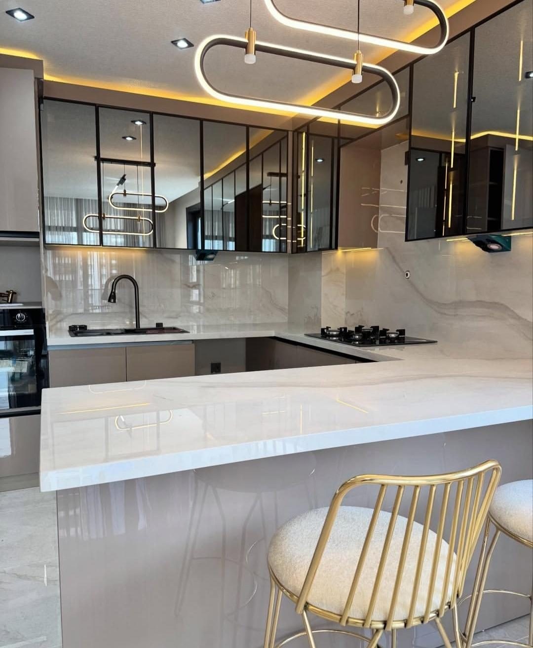 Mermer tezgâhlı U mutfakta oval LED sarkıt ve siyah çerçeveli camlı üst dolaplar